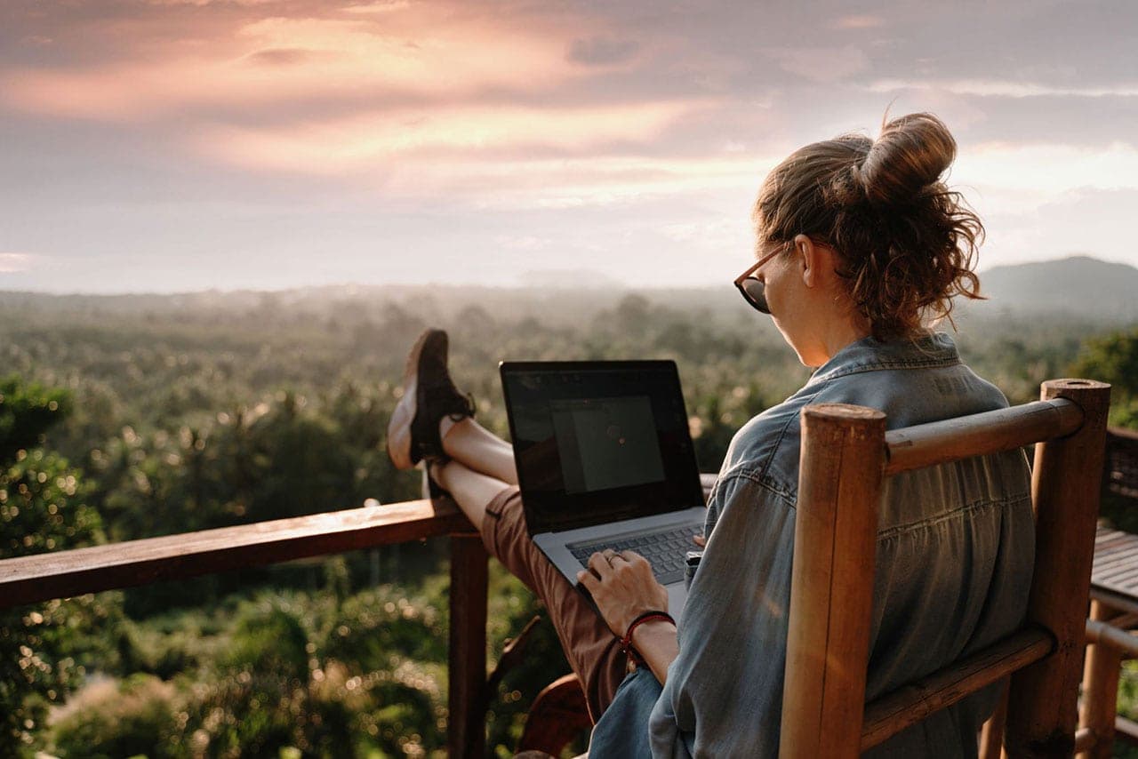 Sandra Seelig arbeitet mit einem Laptop und blickt in die Natur.